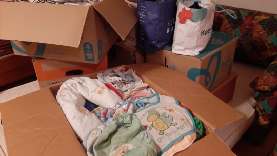 SChachteln und Säcke mit Babybekleidung , Lätzchen und anderen Babysachen.