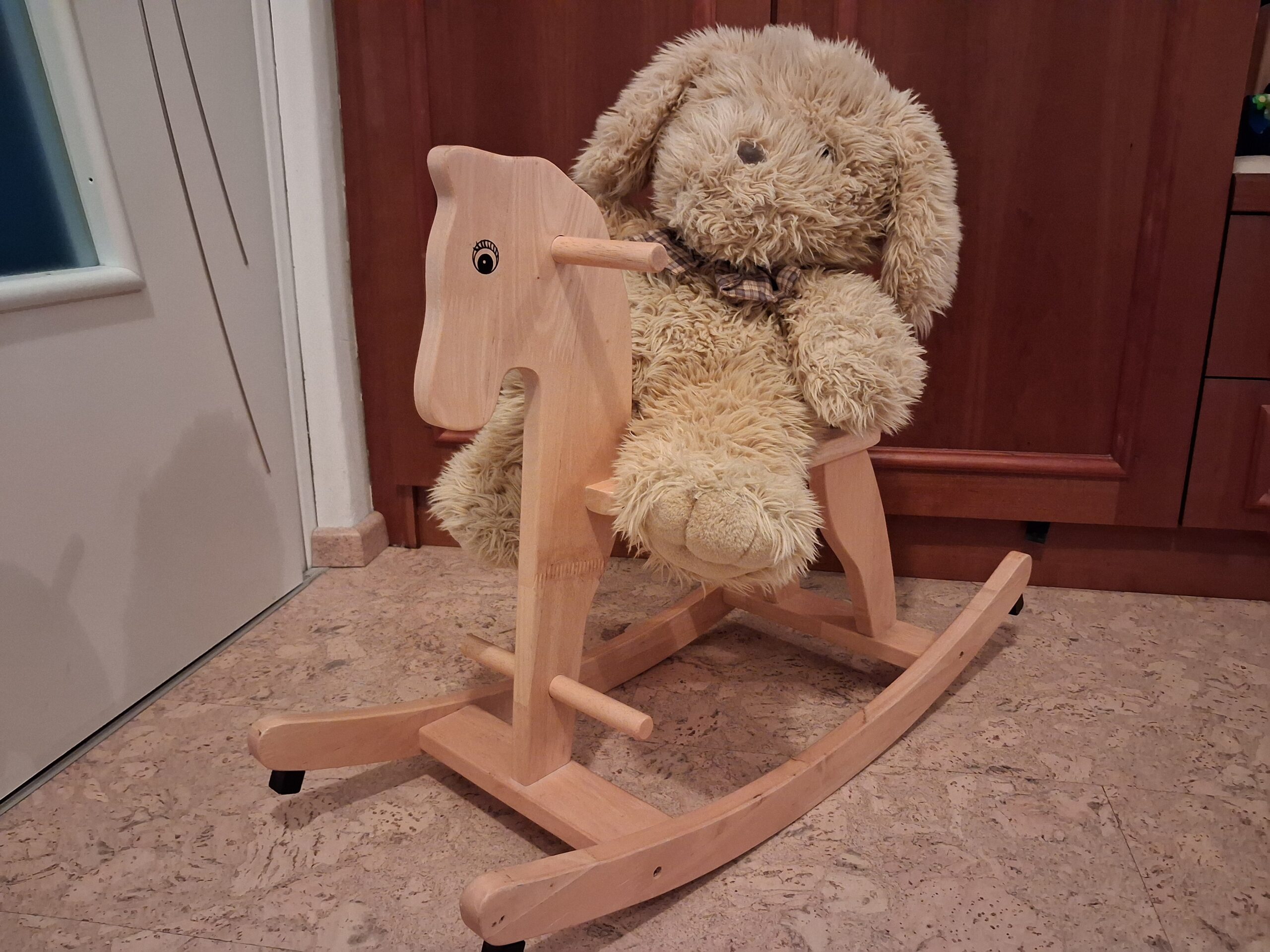 Ein Teddybär sitzt auf einem Schaukelpferd.