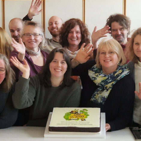 Das Team der Umweltberatung mit Torte winkt in die Kamera