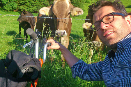 Gerald Franz mit Fahrrad und Kühen im Hintergrund