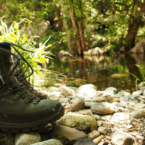 Wanderschuhe stehen am Ufer eines Baches.