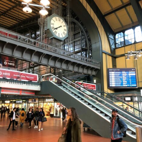 Belebte Bahnhofshalle mit großer Bahnhofsuhr
