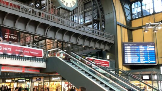 Belebte Bahnhofshalle mit großer Bahnhofsuhr
