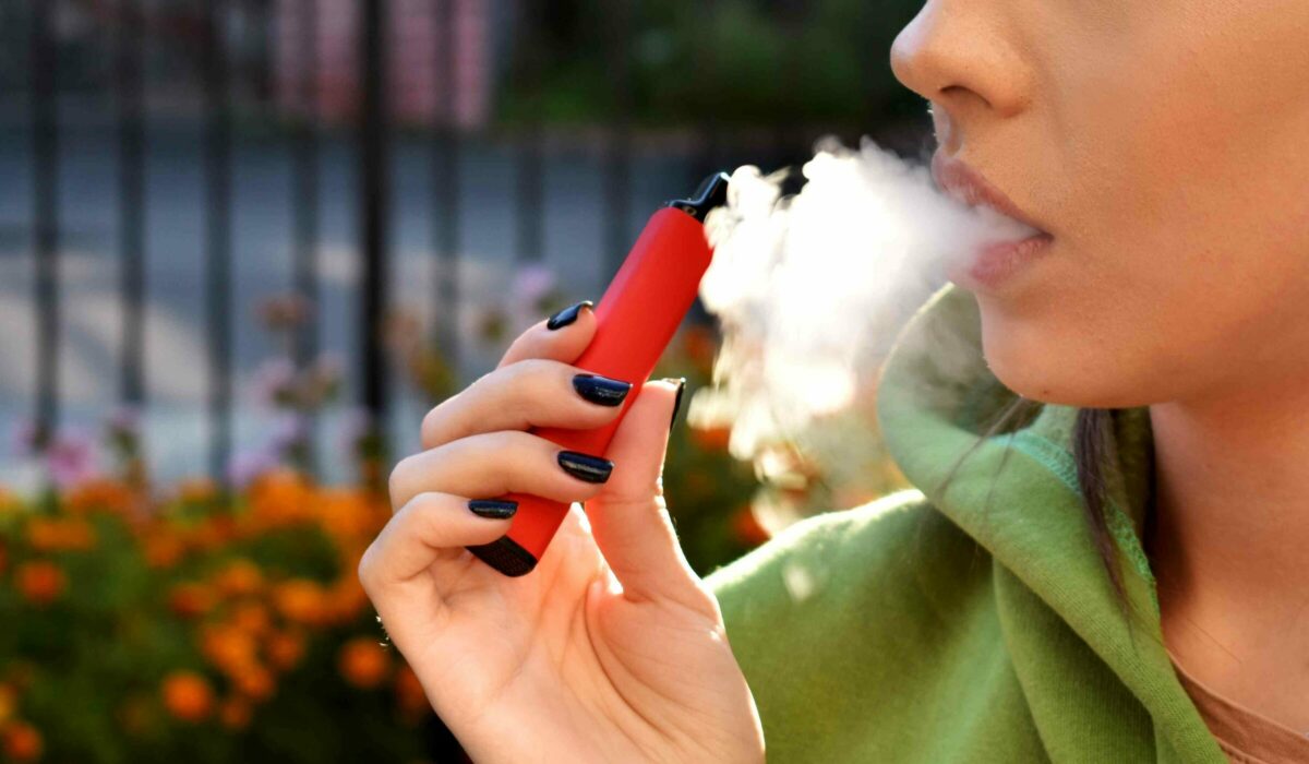 Frau raucht eine rote E-Zigarette