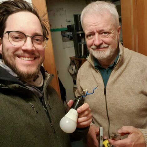 Vater und Sohn helfen Gegenstände im Repair-Cafe zu reparieren.