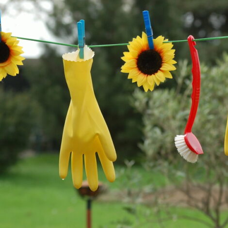 Gelbe Gummihandschuhe und Spülbürste hängen an Wäscheleine.