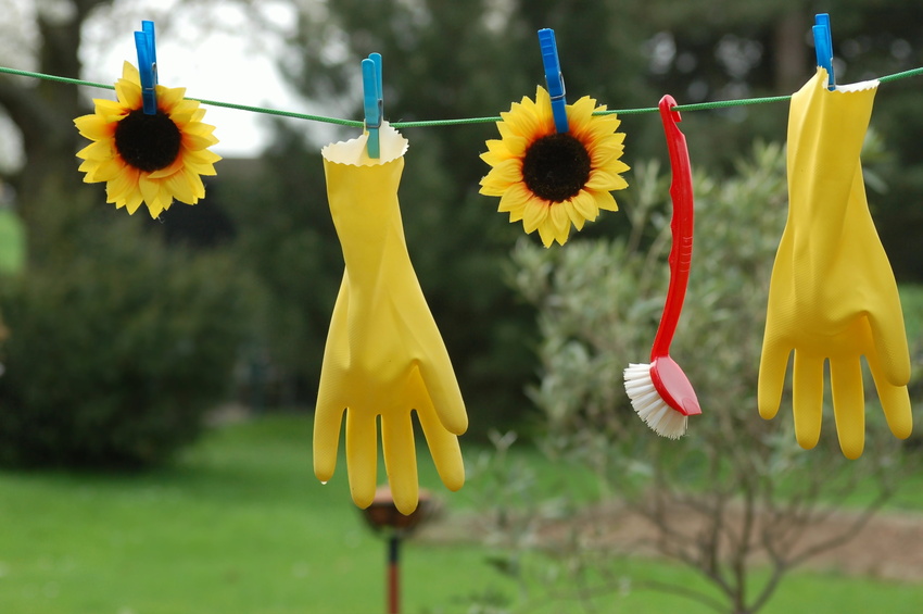 Gelbe Gummihandschuhe und Spülbürste hängen an Wäscheleine.