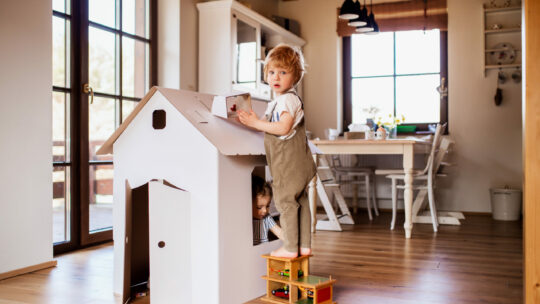 Kinder beim spielen zuhause mit einem Puppenhaus