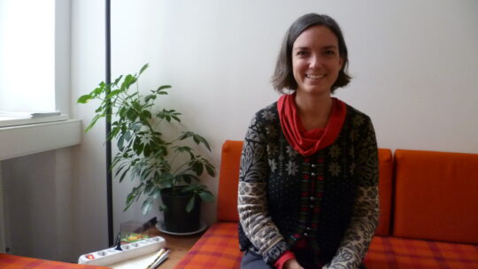 Helene Pattermann von zero waste sitzt auf oranger Sitzecke in ihrer Wohnung.
