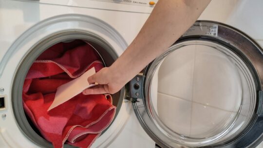 Ein Waschblatt wird zur Wäsche in die Waschmaschine gesteckt.