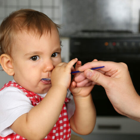 Baby wird in der Küche mit Brei gefüttert.