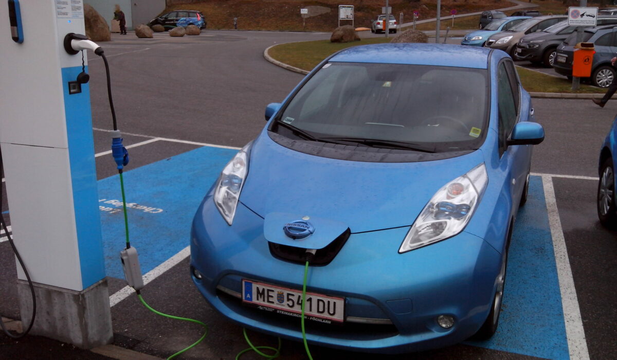 Elektroauto auf einem Parkplatz an einer Ladesäule angeschlossen.