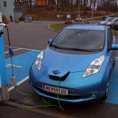 Elektroauto auf einem Parkplatz an einer Ladesäule angeschlossen.