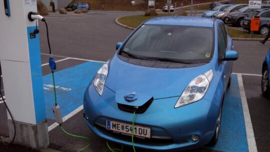 Elektroauto auf einem Parkplatz an einer Ladesäule angeschlossen.