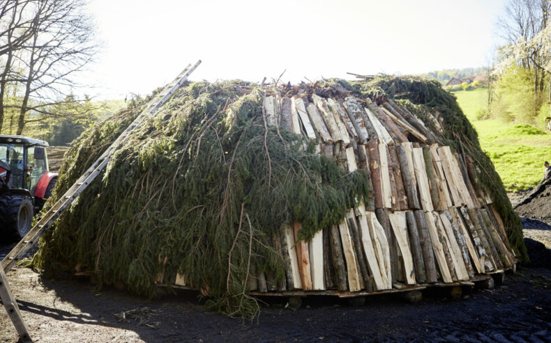 Das Holz für die Holzkohle wird abgedeckt.