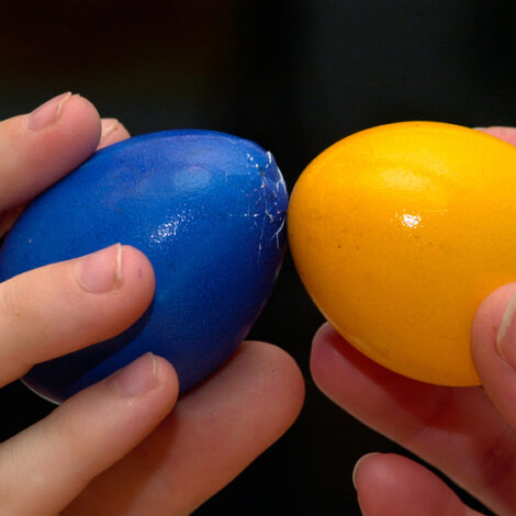 zwei Kinder mit einem blauen und einem gelben Ei beim Eierpecken