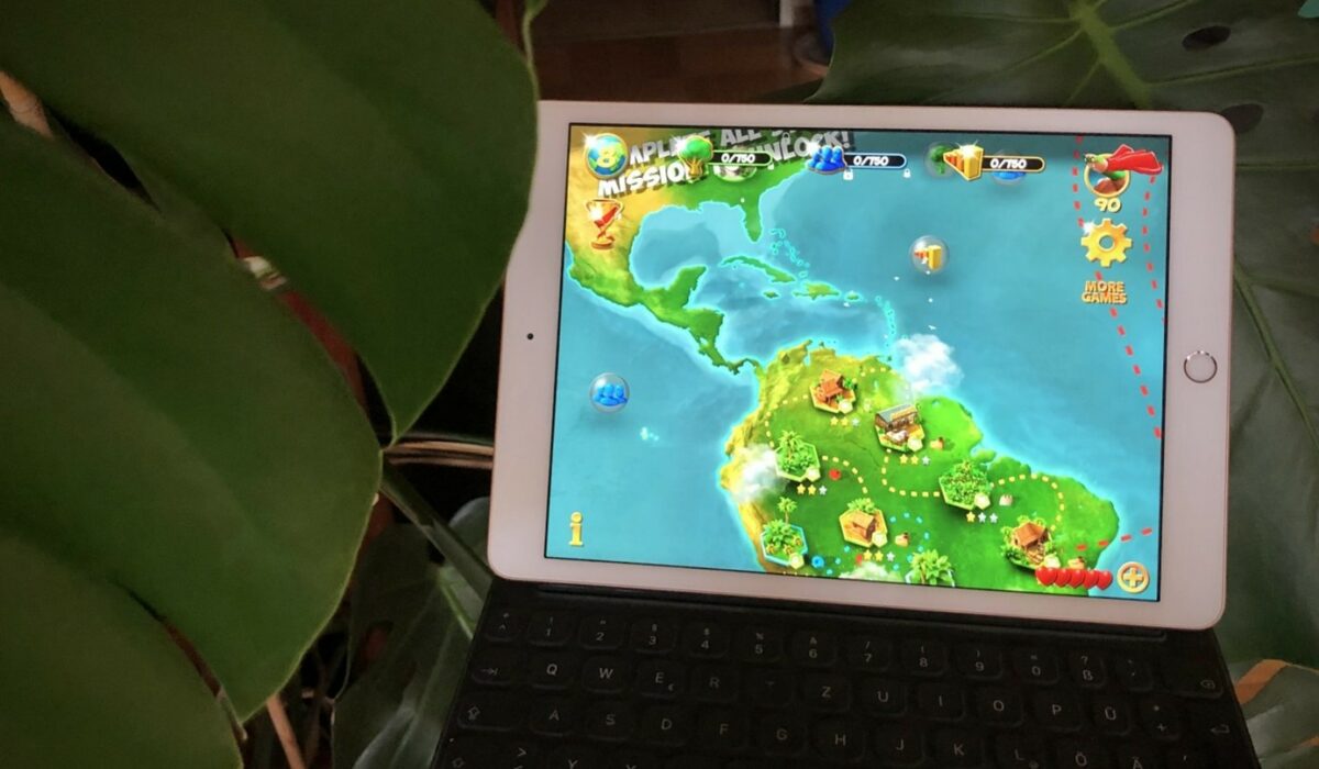 Tablet mit Online Umweltspiel neben große Zimmerpflanze
