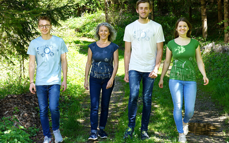 Vier Personen mit handbedruckten T-Shirts gehen durch den Wald