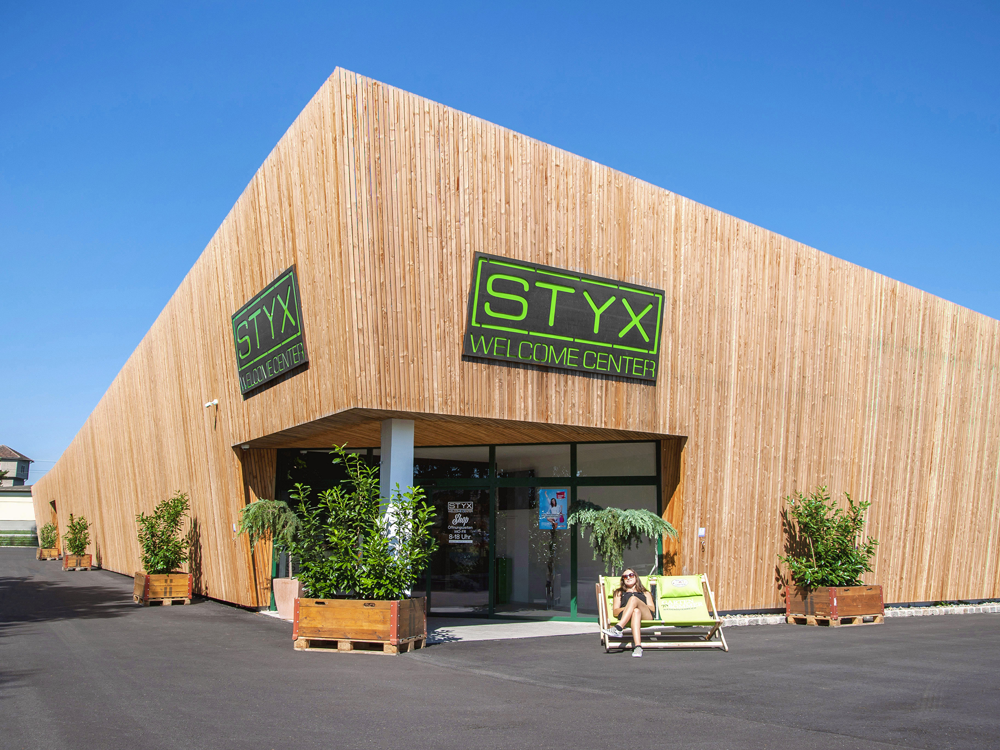 Firmengebäude Styx mit moderner Holzfassade und Trögen mit Pflanzen davor