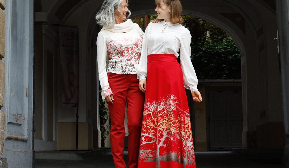 zwei Models mit edler, rot-weißer Kleidung von peaces Mode stehen in Torbogen