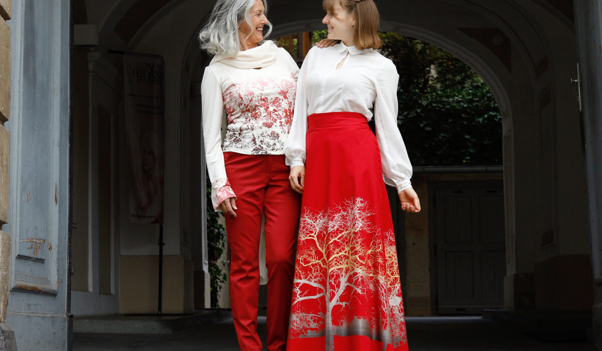 zwei Models mit edler, rot-weißer Kleidung von peaces Mode stehen in Torbogen