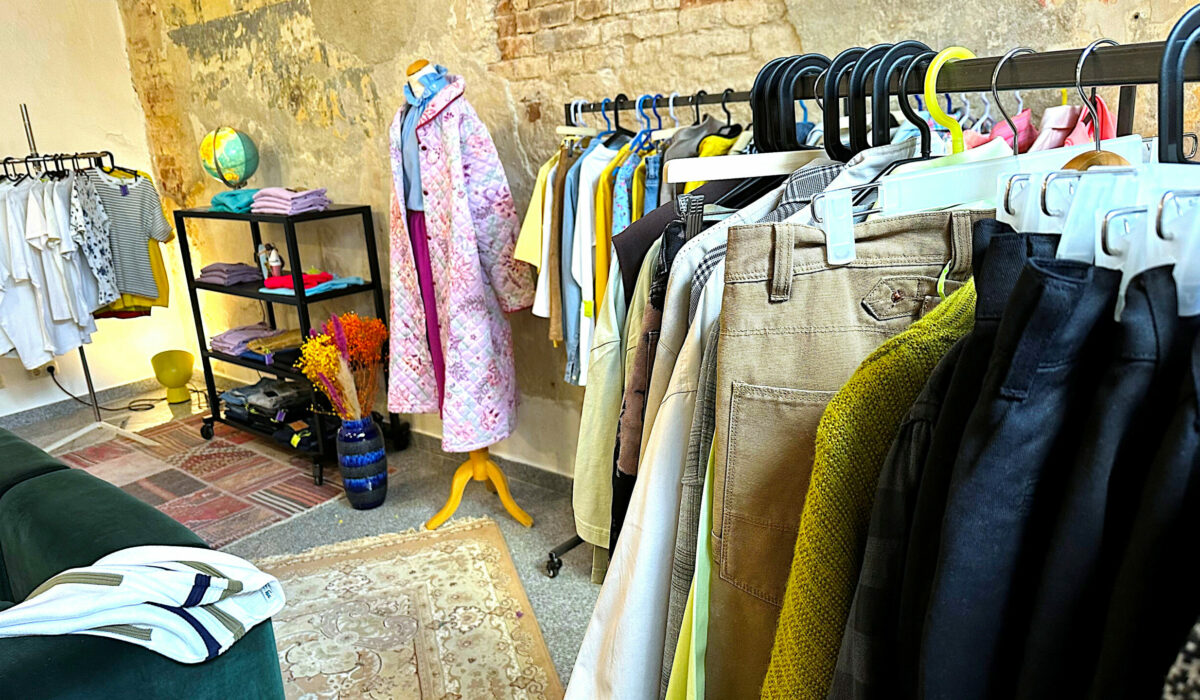 Kleiderständer mit gebrauchter Kleidung in Second Hand Laden