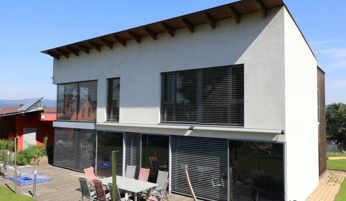 Passivhaus mit Raffstores und Gartenmöbeln auf der Terrasse.