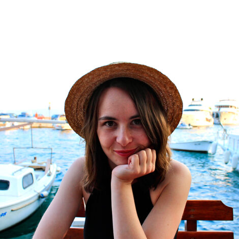Stefanie Reichl in einem Hafen auf einer Holzbank sitzend