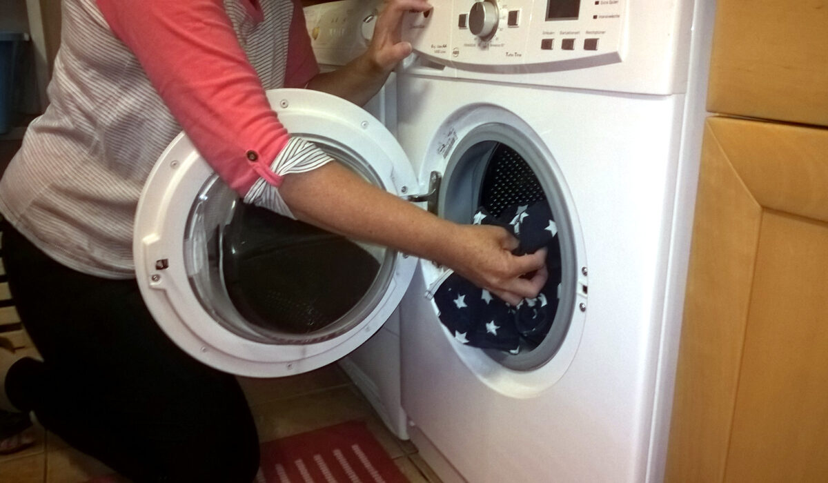 Frau befüllt die Wäschetrommel einer Waschmaschine