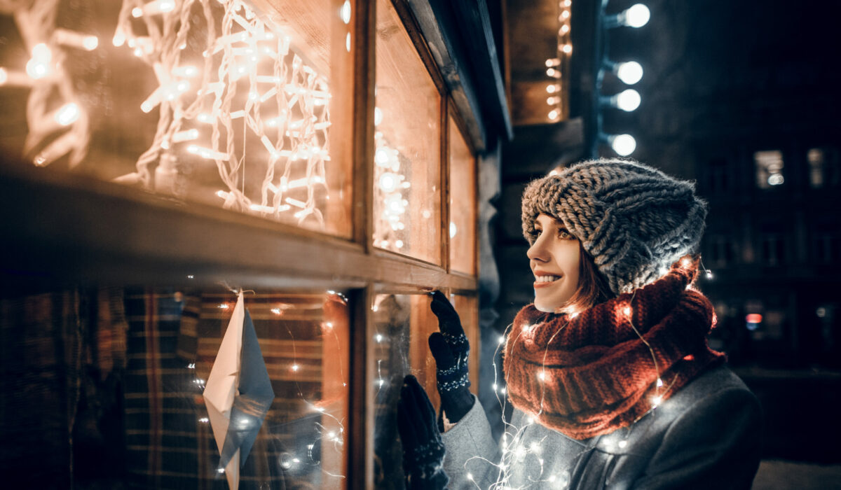 Frau bewundert Weihnachtsbeleuchtung auf Weihnachtsmarkt