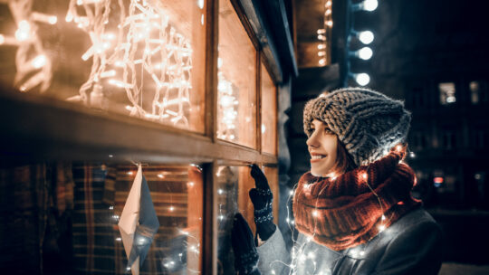 Frau bewundert Weihnachtsbeleuchtung auf Weihnachtsmarkt