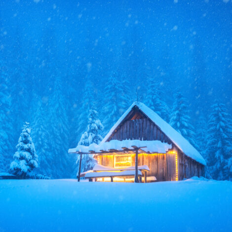 Ein einsames, beleuchtete Holzhütte inmitten eines schneebedeckten Waldes