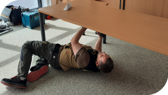 Handwerker schraubt unter einem Schreibtisch