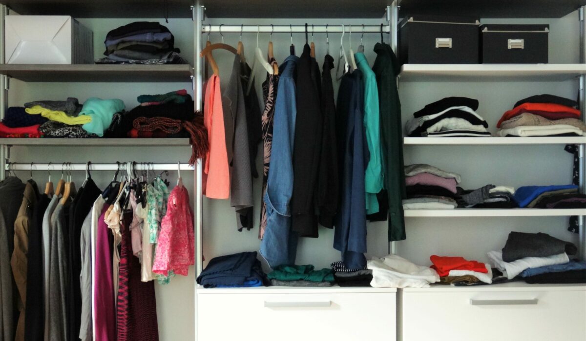 Ankleidezimmer mit vielen Kleidern und Pullis auf Regalen und Stangen