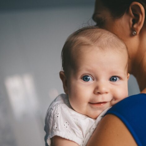 Baby lächelt über die Schulter der Mutter