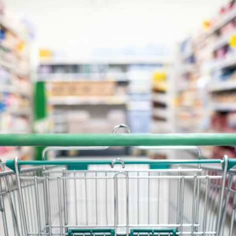Einkaufswagen im Supermarkt zwischen gefüllten Regalen