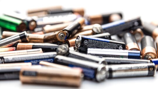 Eine große Menge Batterien, unordentlich gestapelt auf einer festen Oberfläche