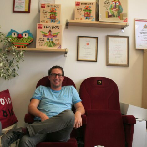 Mag. Stefan Friedrich sitzt auf alten roten Kinosessel in seinem Büro