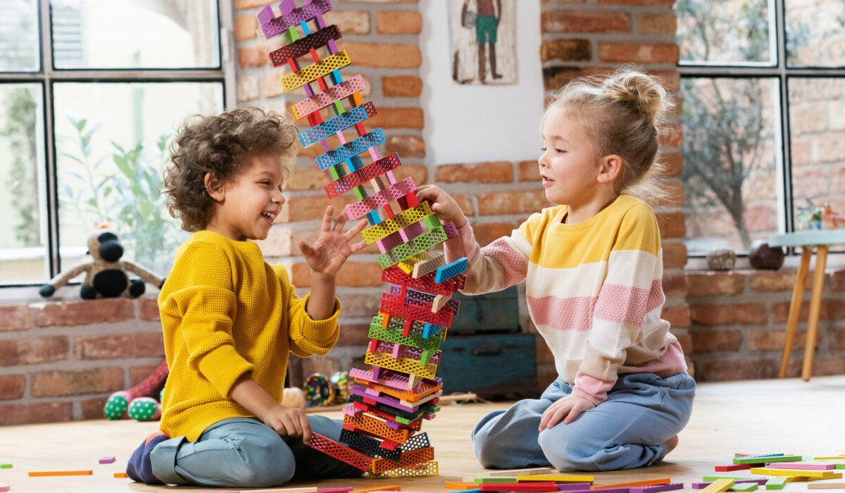 zwei Kinder spielen mit den Bausteinen von bioblo, der gebaute Turm fällt um