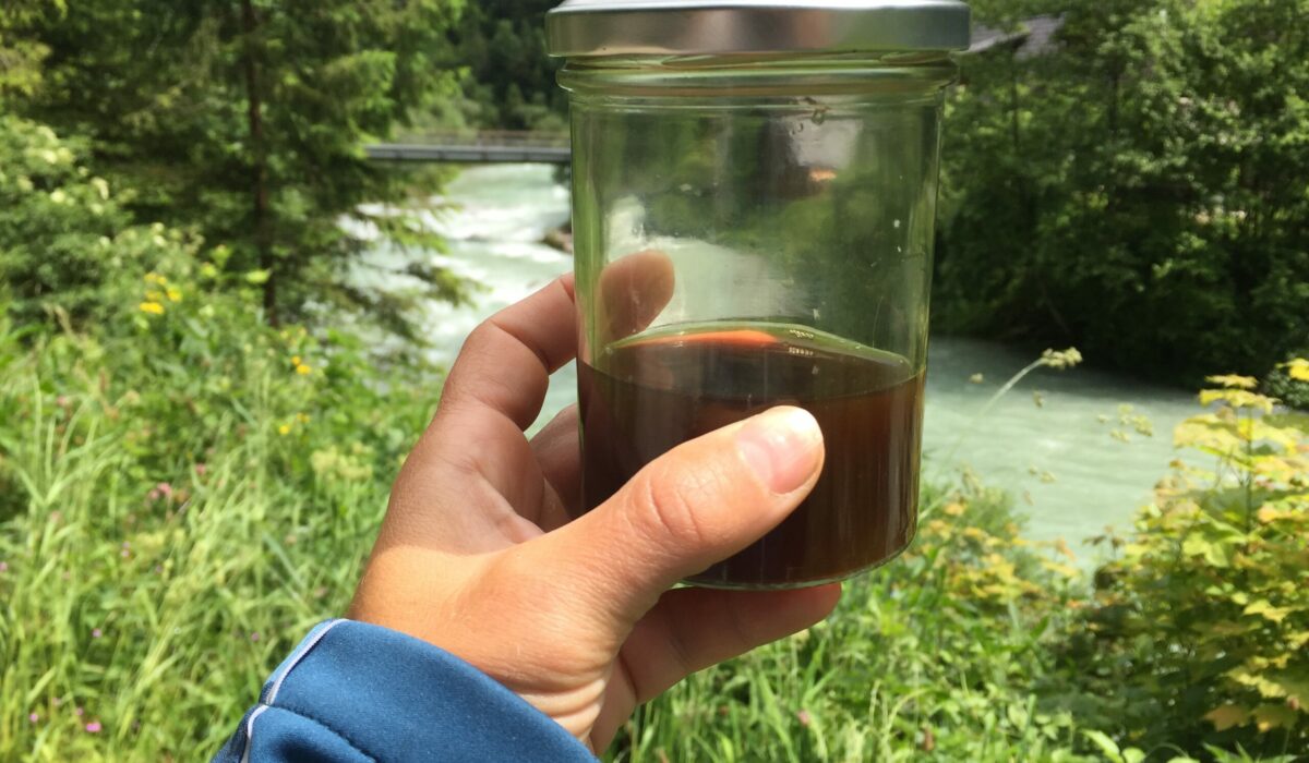 Eine Frau hält ein Schraubglas, gefüllt mit Kaffee hoch.