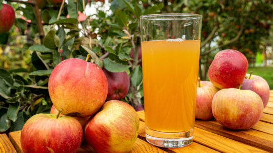 Eine Nahaufnahme von Äpfeln und Apfelsaft auf einem Holztisch