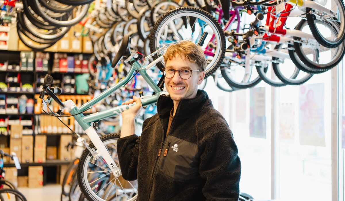 Julian Walkowiak hält ein Kinderfahrrdas in der Hand hoch