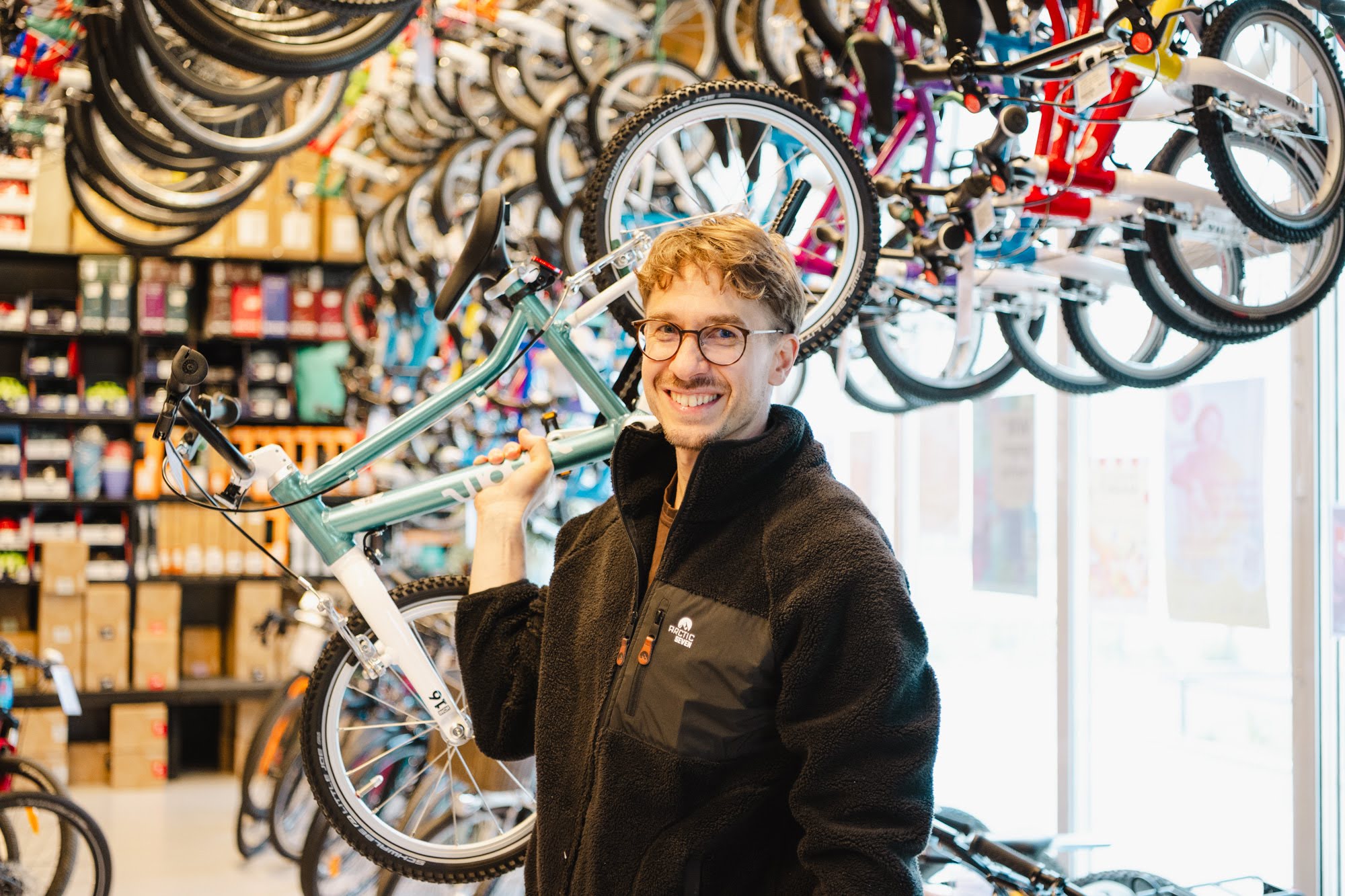 Julian Walkowiak hält ein Kinderfahrrdas in der Hand hoch