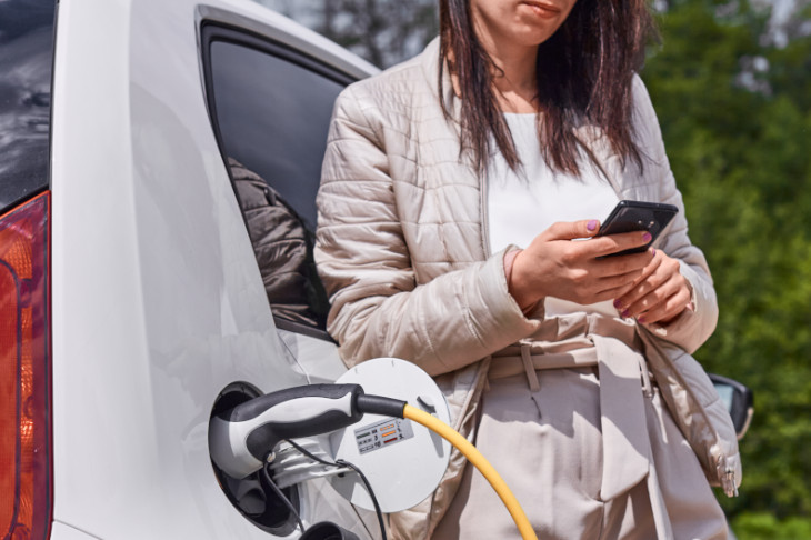 Frau beim Laden eines E-Autos