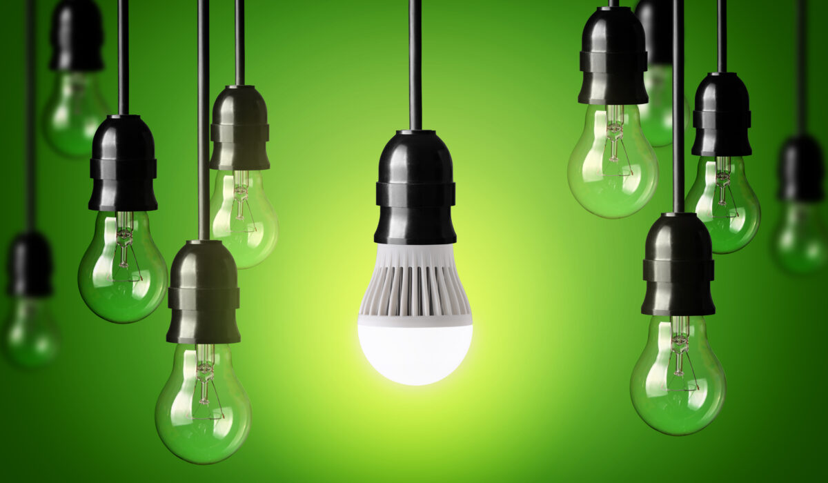 LED-Lampe und einfache Glühbirnen. Grüner Hintergrund.