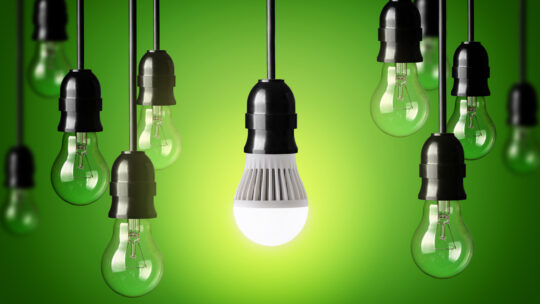 LED-Lampe und einfache Glühbirnen. Grüner Hintergrund.