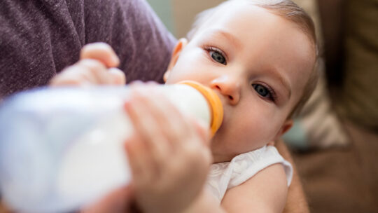Vater füttert Baby mit einem Milchfläschchen