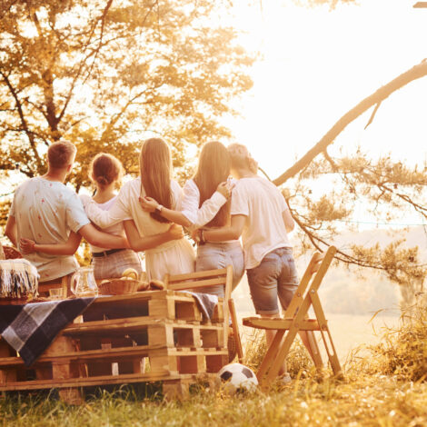 Eine Gruppe von jungen Menschen umarmen sich und betrachten den Sonnenuntergang. Eine Gruppe junger Leute verbringt ihre Freizeit in der Natur.