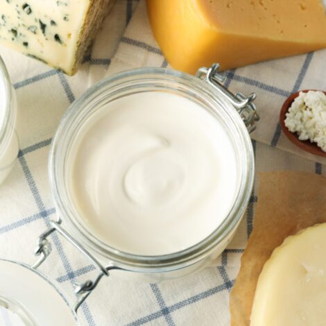 Milchprodukte wie Butter, Milch, Frischkäse und Hartkäse auf einem karierten Tischtuch