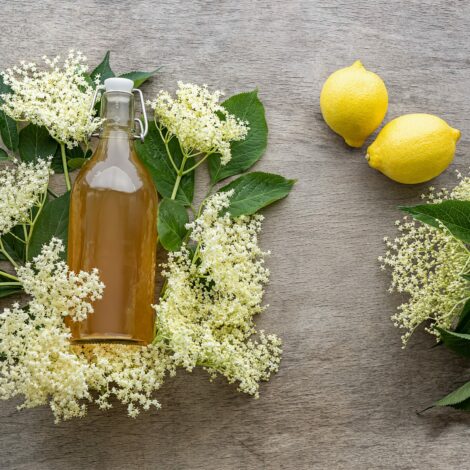 Holunderblütensirup in einer Flasche mit Holunderblüten und Zitronen